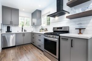 Well-furnished modern kitchen with steel and wood cabinetry, shiny wooden floors, black glass oven, and scenic view from the kitchen.